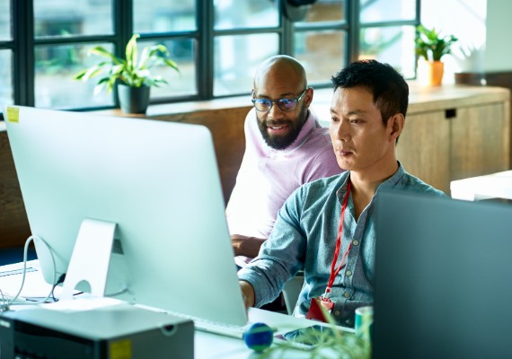 Two men working on a computer together