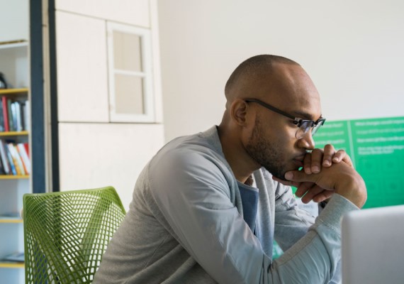 Man sitting with his hands clasped in front of his face